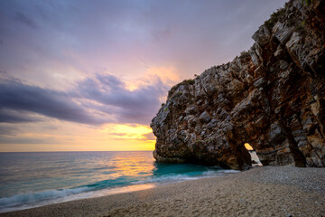 Seascape at sunrise. The sun rises over the sea and illuminates it. Long exposure. A large rock...