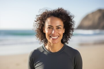 Portrait of smiling young woman with curly hair standing on the beach