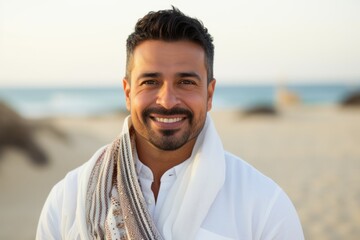 Portrait of a handsome young man smiling and looking at camera on the beach