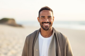 portrait of smiling african american man in coat on beach