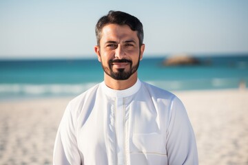 Portrait of smiling muslim man standing on the beach at sunny day