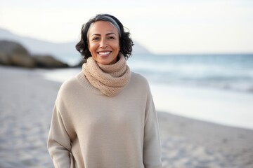 Portrait of smiling woman wearing warm sweater and scarf on the beach