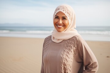Portrait of smiling muslim woman in hijab standing on the beach