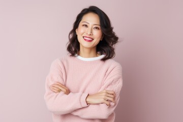 Fototapeta premium Portrait of a Chinese woman in her 40s in a pastel or soft colors background wearing a cozy sweater