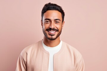 Fototapeta premium Medium shot portrait of a Saudi Arabian man in his 30s in a pastel or soft colors background wearing a chic cardigan