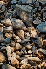 Cluster of many rough stones on the ground with sunlight on them