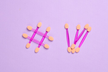 Makeup applicators in hashtag form on a pink background