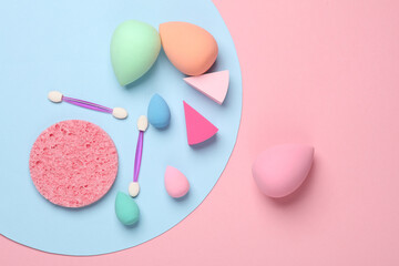 Make-up sponge, cosmetic blenders and applicators for makeup on pink blue background. Beauty products. Top view. Flat lay