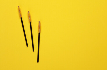 Brushes for combing eyelashes on yellow background. Beauty concept