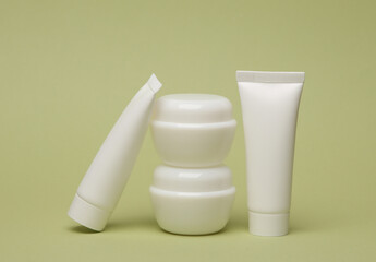 White blank cream tube and jars on green background. Template for design, mockup. Beauty concept