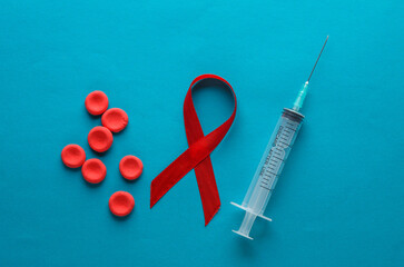 Syringe and red hiv, aids awareness ribbon, Red blood cells on blue background