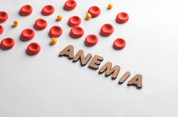 Red blood cells model and word anemia on white background. Blood disease