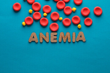 Red blood cells model and word anemia on blue background. Blood disease