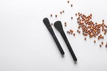 Black make-up brushes with powder ball on white background. Flat lay, beauty concept