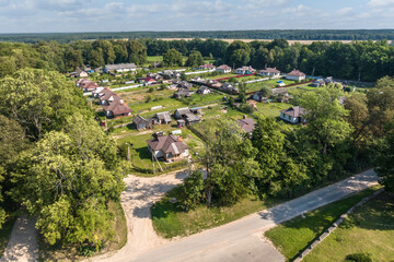 panoramic aerial view of eco village with wooden houses, gravel road, gardens and orchards