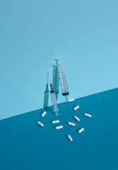 Syringe with pills on blue background with shadow. Creative layout
