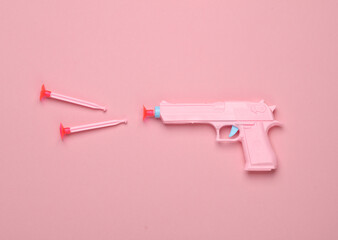 Plastic pistol on a pink background. Creative layout. Minimalism