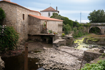 Fototapeta na wymiar Dried up River Este in Portugal during drought in summer. Old stone mill buildings on bank.