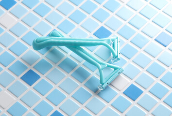 Plastic razors on blue tiles. Beauty concept.