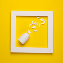 Pills bottle in white frame on yellow background. Creative layout. Minimalism