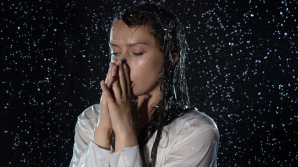 young woman in the rain, getting wet through, wet clothes and water running down her face....