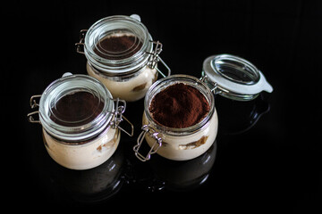 Homemade Italian tiramisu in glass on black background.