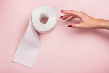 Roll of toilet paper and woman's hand on pink background. International toilet paper day. Top view