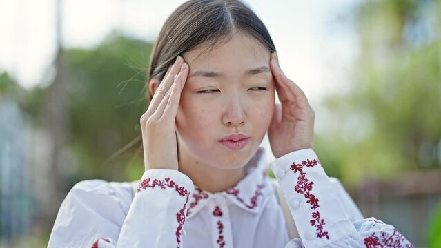 Young chinese woman suffering for headache at street