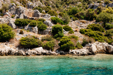 Fototapeta na wymiar Beautiful view of the Mediterranean Sea with yachts. Picturesque landscape of blue ocean and green mountains on a sunny summer day. The sunken city of Kekova, Türkiye - 28 July 2023