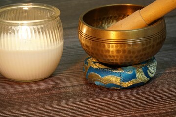 Hand-crafted Tibetan bell on a wooden surface, with a flickering candle