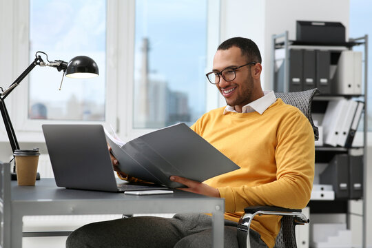 Young man working with documents at table in office
