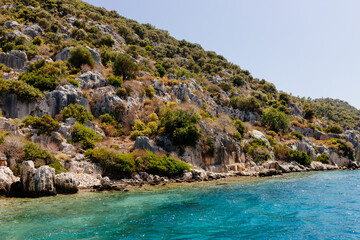 Obraz premium Beautiful view of the Mediterranean Sea with yachts. Picturesque landscape of blue ocean and green mountains on a sunny summer day. The sunken city of Kekova, Türkiye - 28 July 2023