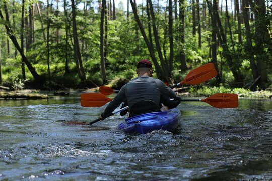 Rear view of a male enjoying a tranquil kayaking experience on the Drawa River in Poland