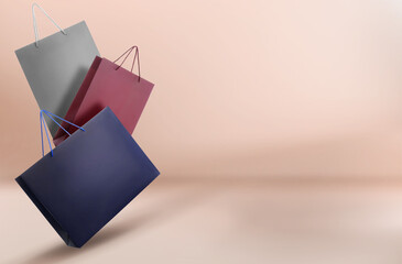 Hot sale. Colorful shopping bags in air on pink beige gradient background, space for text