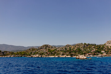 Naklejka na ściany i meble Beautiful view of the Mediterranean Sea with yachts. Picturesque landscape of blue ocean and green mountains on a sunny summer day. The sunken city of Kekova, Türkiye - 28 July 2023