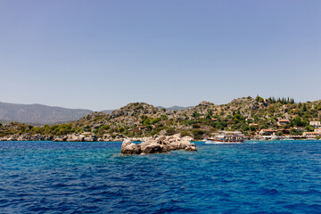 Naklejka premium Beautiful view of the Mediterranean Sea with yachts. Picturesque landscape of blue ocean and green mountains on a sunny summer day. The sunken city of Kekova, Türkiye - 28 July 2023
