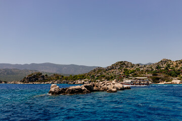Beautiful view of the Mediterranean Sea with yachts. Picturesque landscape of blue ocean and green mountains on a sunny summer day. The sunken city of Kekova, Türkiye - 28 July 2023