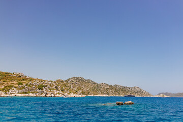 Naklejka premium Beautiful view of the Mediterranean Sea with yachts. Picturesque landscape of blue ocean and green mountains on a sunny summer day. The sunken city of Kekova, Türkiye - 28 July 2023