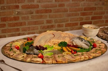 Delicious-looking boiled fish decorated with colorful vegetables, fruits, and meat on the table