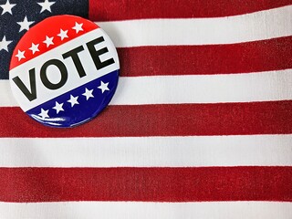 Close-up of a red, white, and blue campaign vote button on an American flag