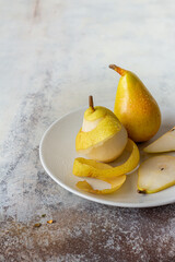 Ripe yellow pears on a white plate and an old white table, food composition in a rustic style, healthy eating concept, close-up., copy space.