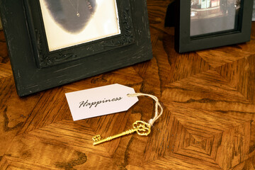 A gold key with tag attached reading happiness