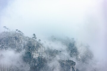Scenic rocky landscape shrouded in mist against the cloudy sky