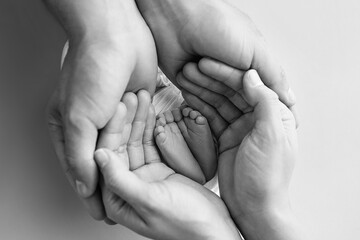 The palms of the father, the mother are holding the foot of the newborn baby.