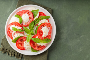 Fresh italian caprese salad with mozzarella and tomatoes on white plate. Top view. Copy space