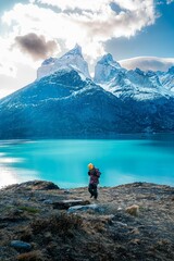 Adult hiker looking at rocky snowy mountains in Torres del Paine National Park, Chile