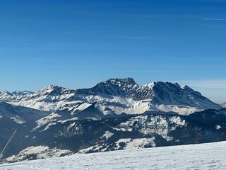 Fototapeta premium Mesmerizing landscape of a snowy field on the background of mountains on a sunny day