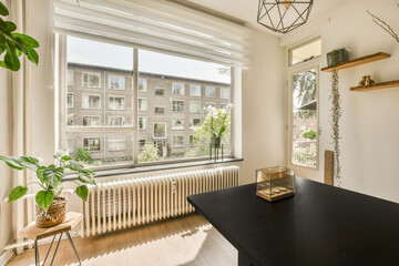 a living room with a window and radiaing on the wall, in front of it is a view of an urban neighborhood