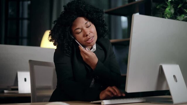 Nervous stressed young businesswoman typing quickly on computer hurry up scream and warning about deadline while having working call conversation by smartphone at modern office workplace