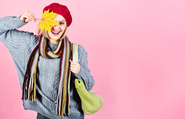 Smiling woman in knitwear with shopping bag covered eye with yellow leaves. Autumn shopping. Happy girl in fashionable autumn clothes. Autumn fashion for women. Season sales. Discount. Copy space.